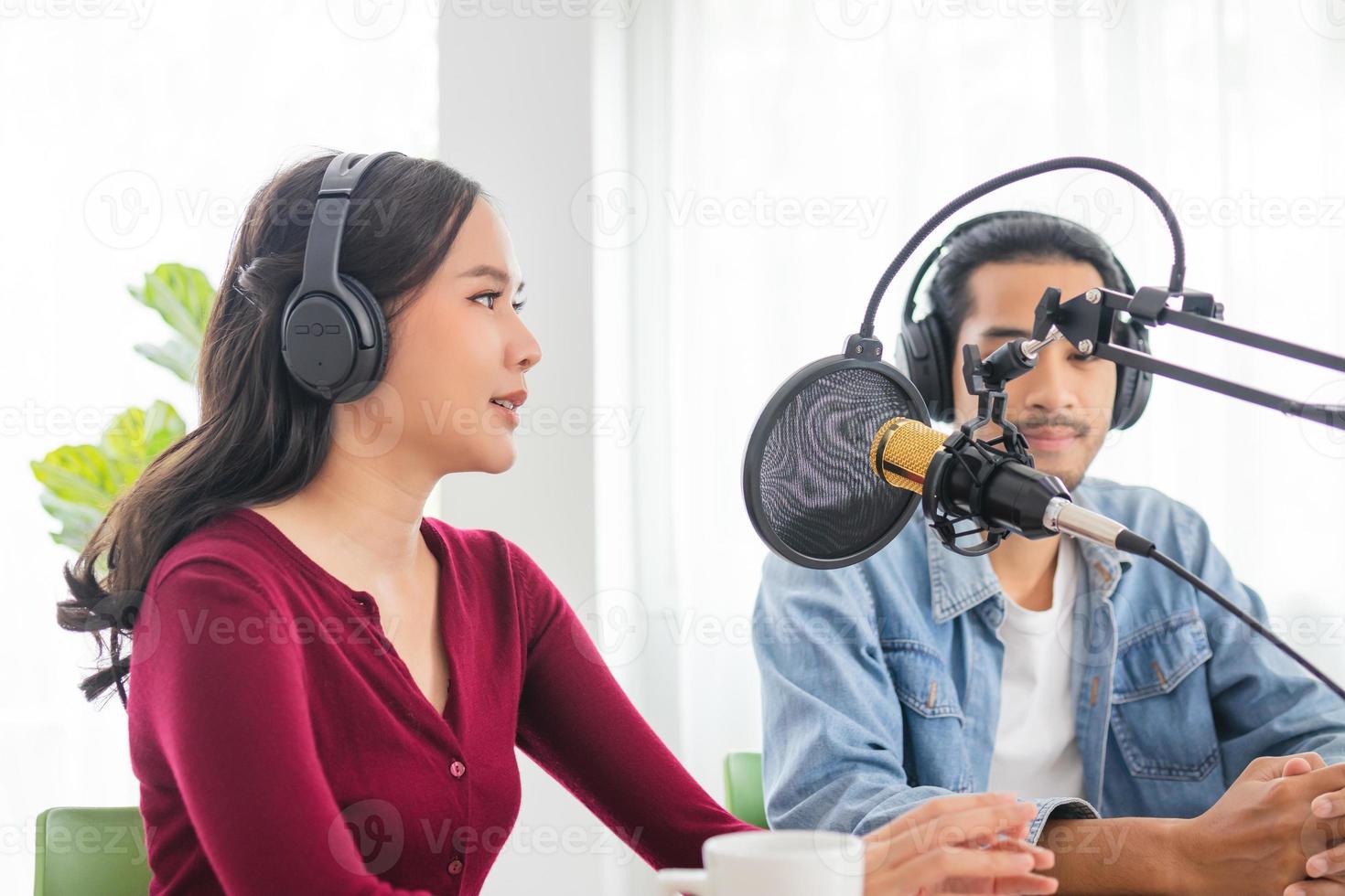 Smile two asian young woman, man radio hosts in headphones, microphone while talk, conversation, recording podcast in broadcasting at studio together. Technology of making record audio concept. photo