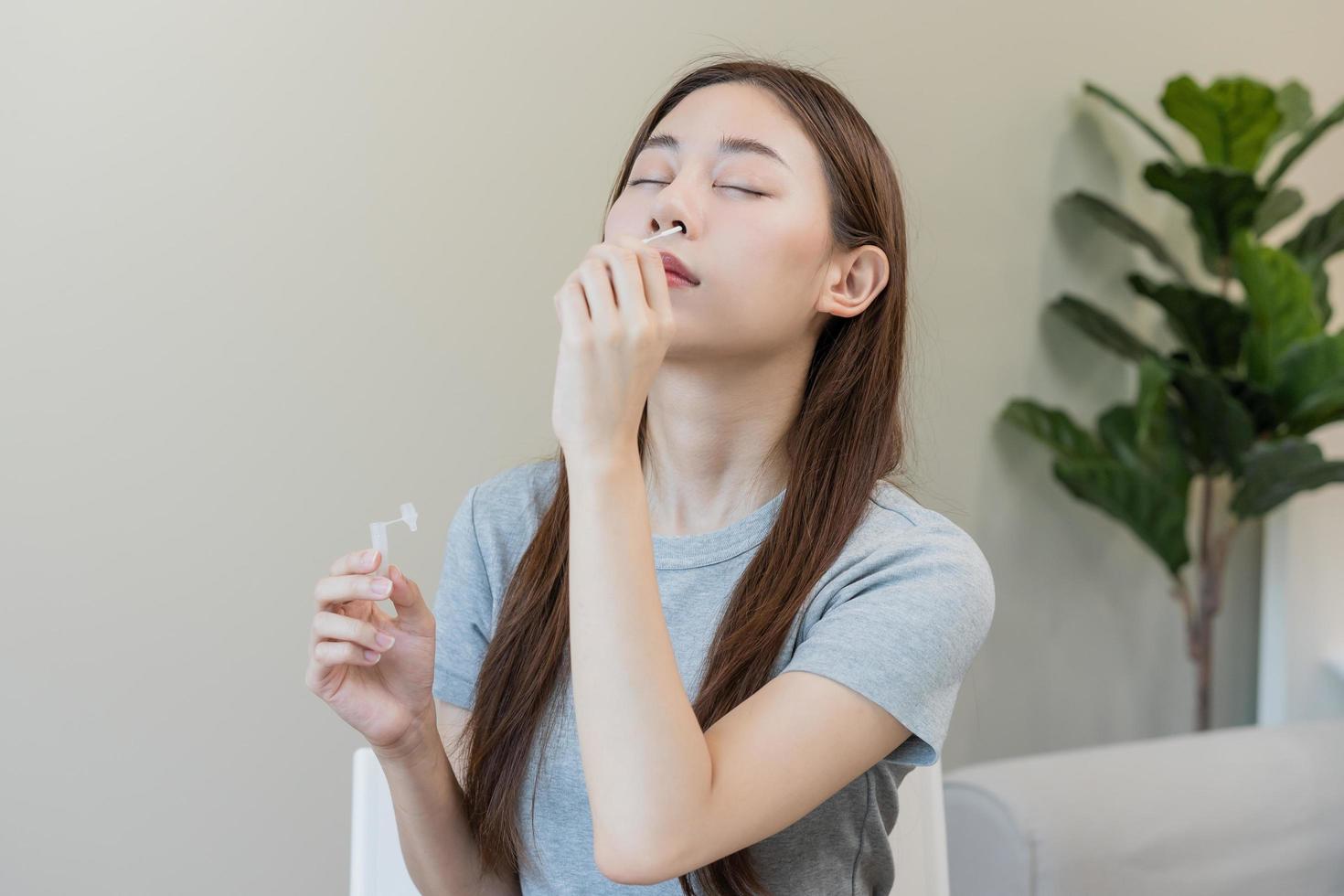 pandemia de enfermedad, asiático joven mujer, niña mano participación atk, antígeno equipo yo prueba. presentando dispositivo nasal, nariz torunda prueba para posible infección de coronavirus, covid-19 a hogar. salud cuidado. foto