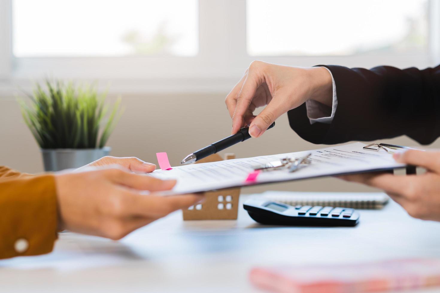 financiero, asiático mujer arrendamiento propietario, agente banquero o unión mano es señalando a contrato de arrendatario, nuevo propietario o inquilino de hogar a firmar firma en compra, alquiler propiedad. inmuebles hipoteca. foto