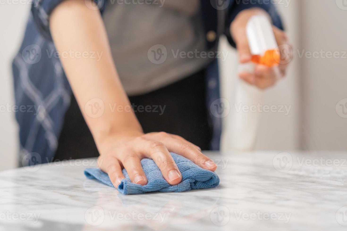 Cleaning hygiene, asian young maid woman, girl hand in using a water sprayer bottle to wipe clean, use blue rag wiping to dust on white marble table in restaurant. Housekeeping cleanup, cleaner. photo