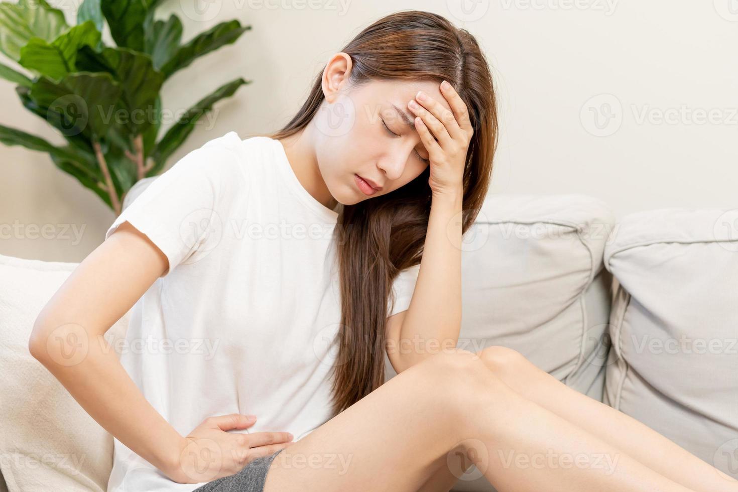 Flatulence asian young woman, girl hand in stomach ache, suffer from food poisoning, abdominal pain and colon problem, gastritis or diarrhoea. Patient belly, abdomen or inflammation, concept. photo