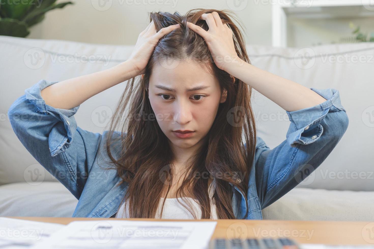 financiero deber asiático mujer, hembra mano en cubrir rostro, sentado en estresado y confuso por calcular gastos desde factura o factura, tener No dinero a pagar, hipoteca o préstamo. deuda, bancarrota o arruinado. foto