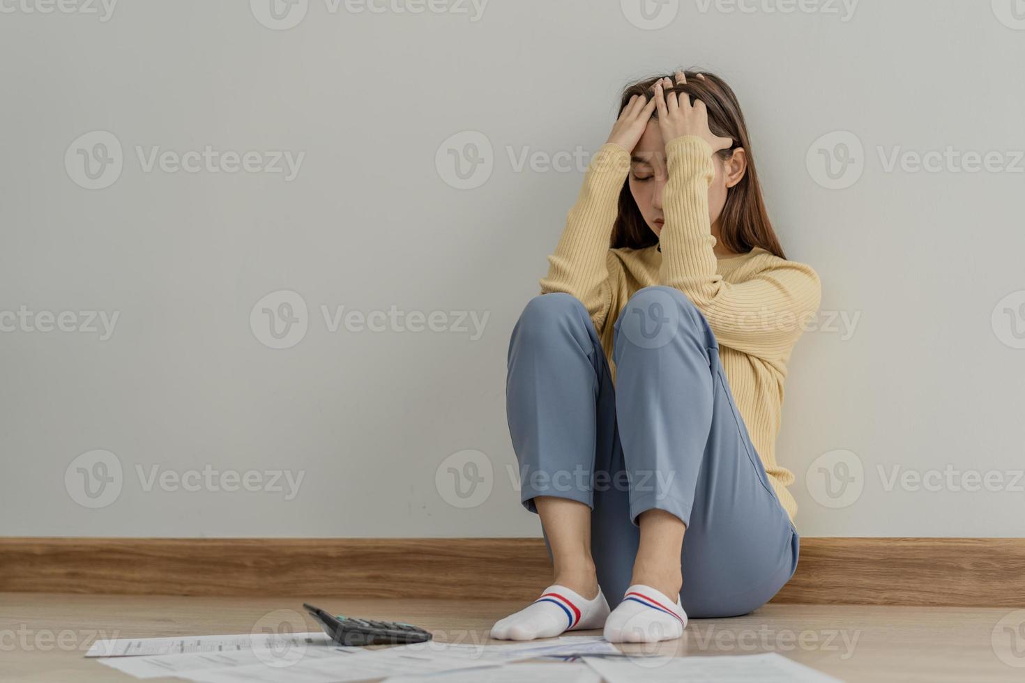 financiero deber asiático mujer, hembra sentado en piso hogar, estresado y confuso por calcular gastos desde factura o factura, tener No dinero a pagar, hipoteca o préstamo. deuda, bancarrota o arruinado concepto. foto