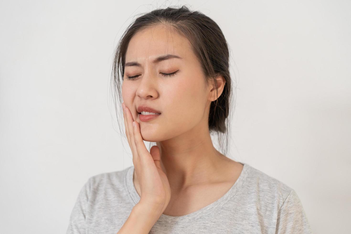 clausura ojos asiático joven mujer conmovedor mejilla, cara expresión desde dolor de muelas, diente decaer o sensibilidad, teniendo diente o dientes problema o inflamación, sufrimiento desde salud. sensible dientes personas foto