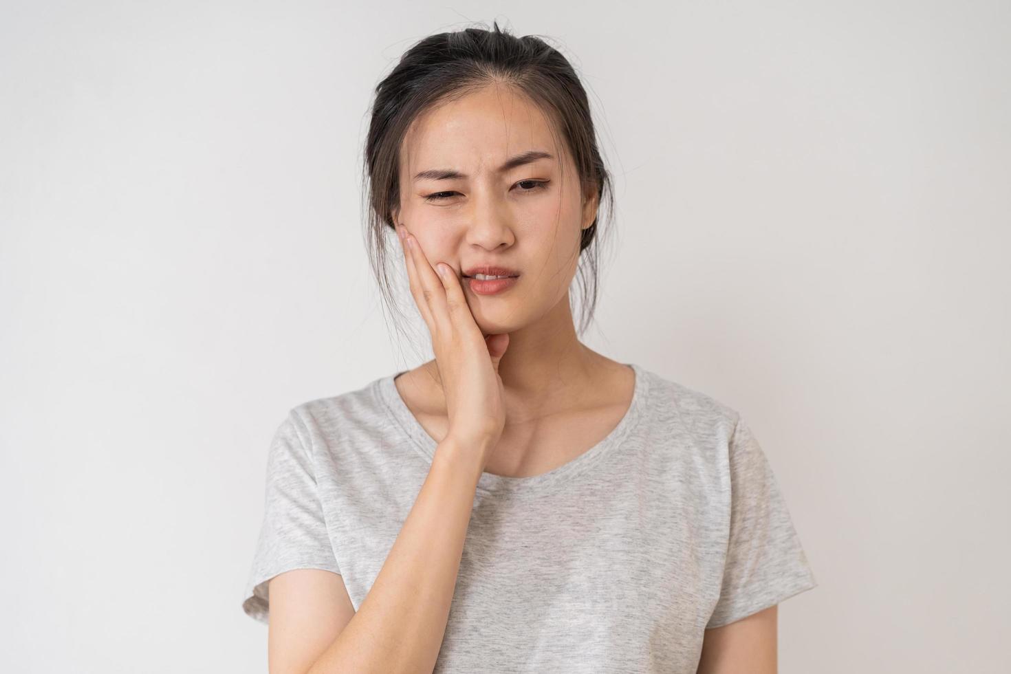 Closing eyes asian young woman touching cheek, face expression from toothache, tooth decay or sensitivity, Having tooth or teeth problem or inflammation, suffering from health. Sensitive teeth people photo