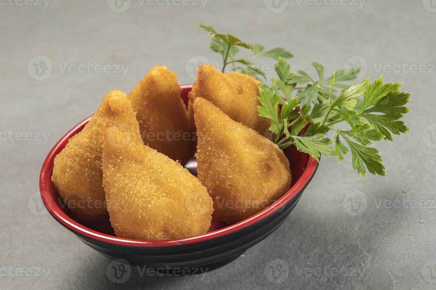 tradicional frito coxinha en plato en pizarra fondo, popular brasileño bocadillo foto