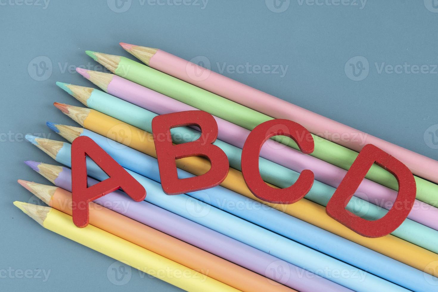 Back to school concept with assorted letters and colored pencils in pastel colors photo