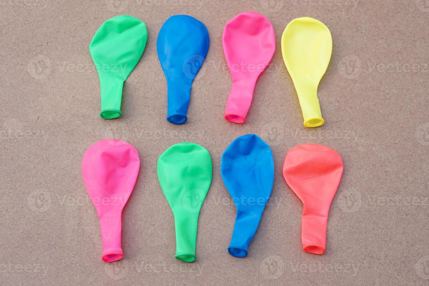 Multi colors  balloons on brown background. Concept,  toy and equipment to play fun games or prepare party. Deflated balloons. photo