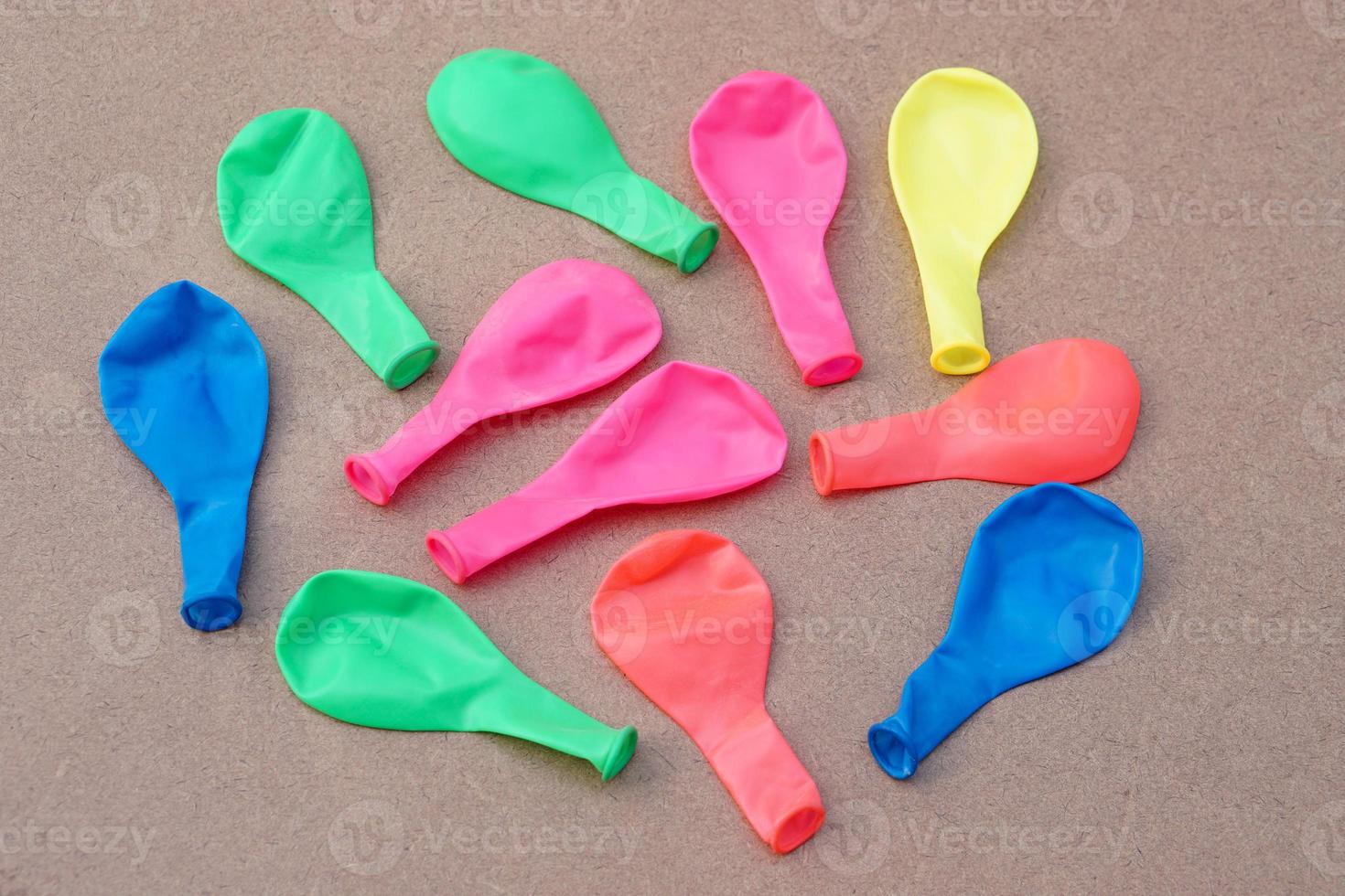 Multi colors  balloons on brown background. Concept,  toy and equipment to play fun games or prepare party. Deflated balloons. photo