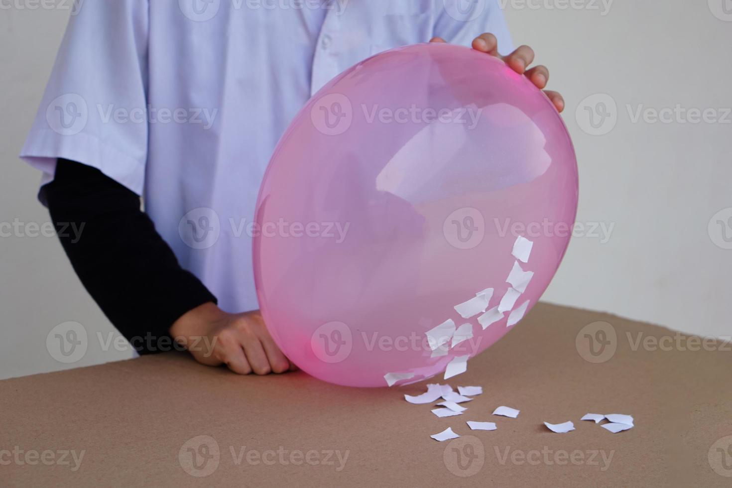 Closeup student do science experiment about static electricty from pink balloon and pieces of paper. Concept, Science project work activity. Learning by doing. Education. photo