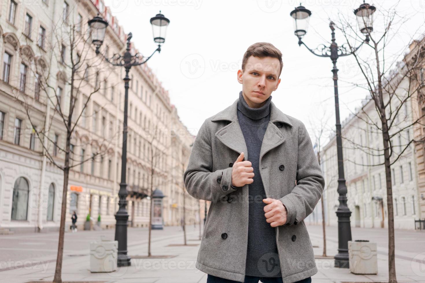 Young man walking down street, autumn or winter cold day. Outdoors, outside. photo