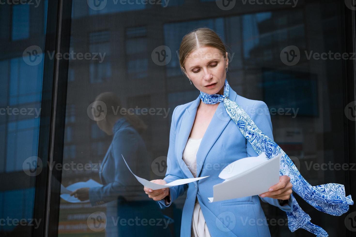 Businesswoman holds documents her hand against  background of an office building photo