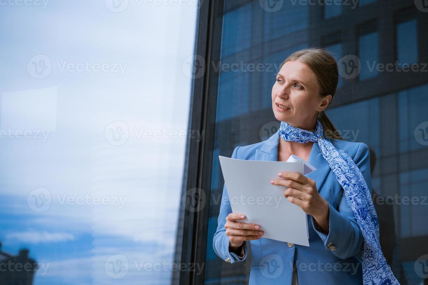 Businesswoman holds documents her hand against  background of an office building photo