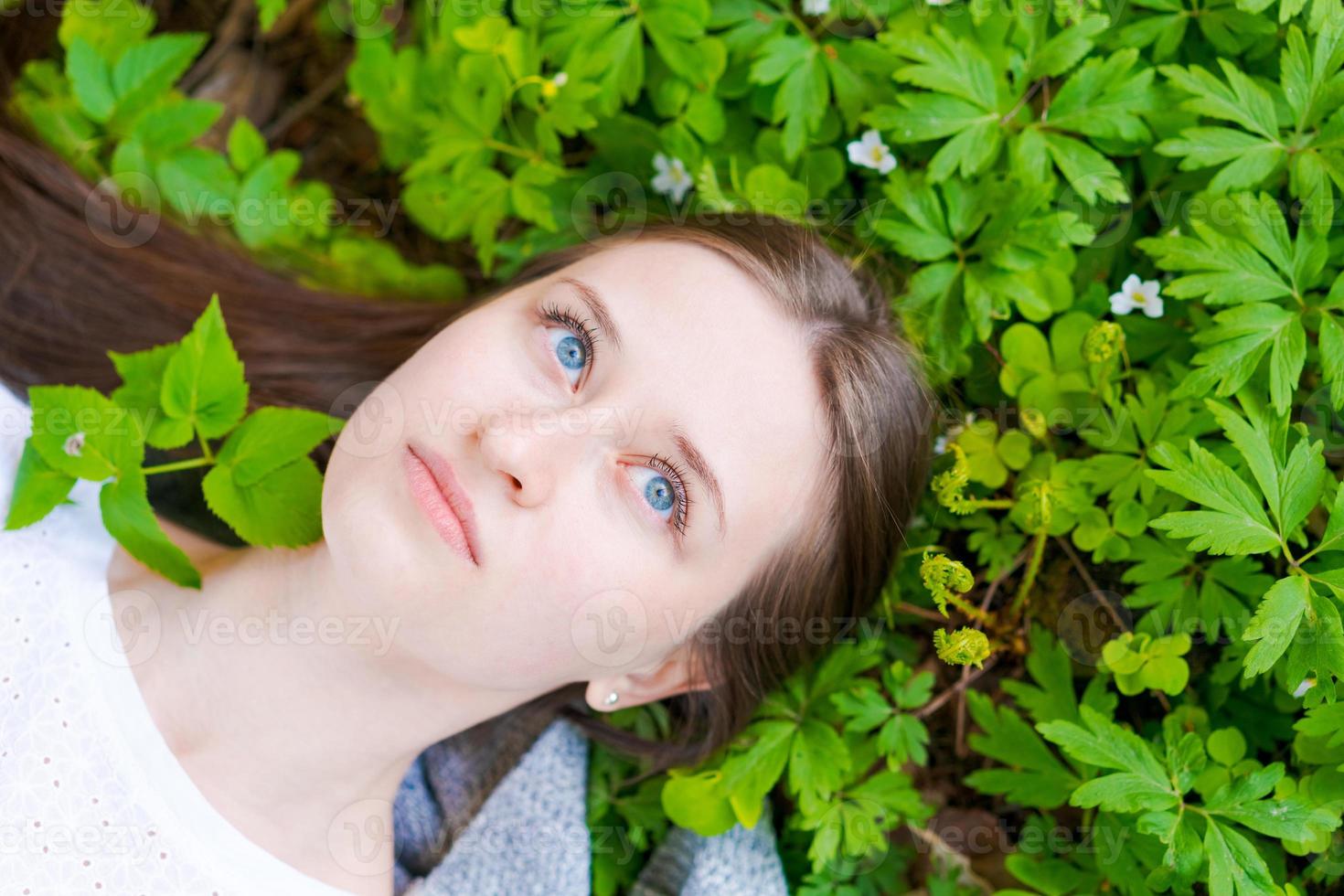 Young woman in casual clothes lies on green, beautiful lawn, dreams in spring. photo