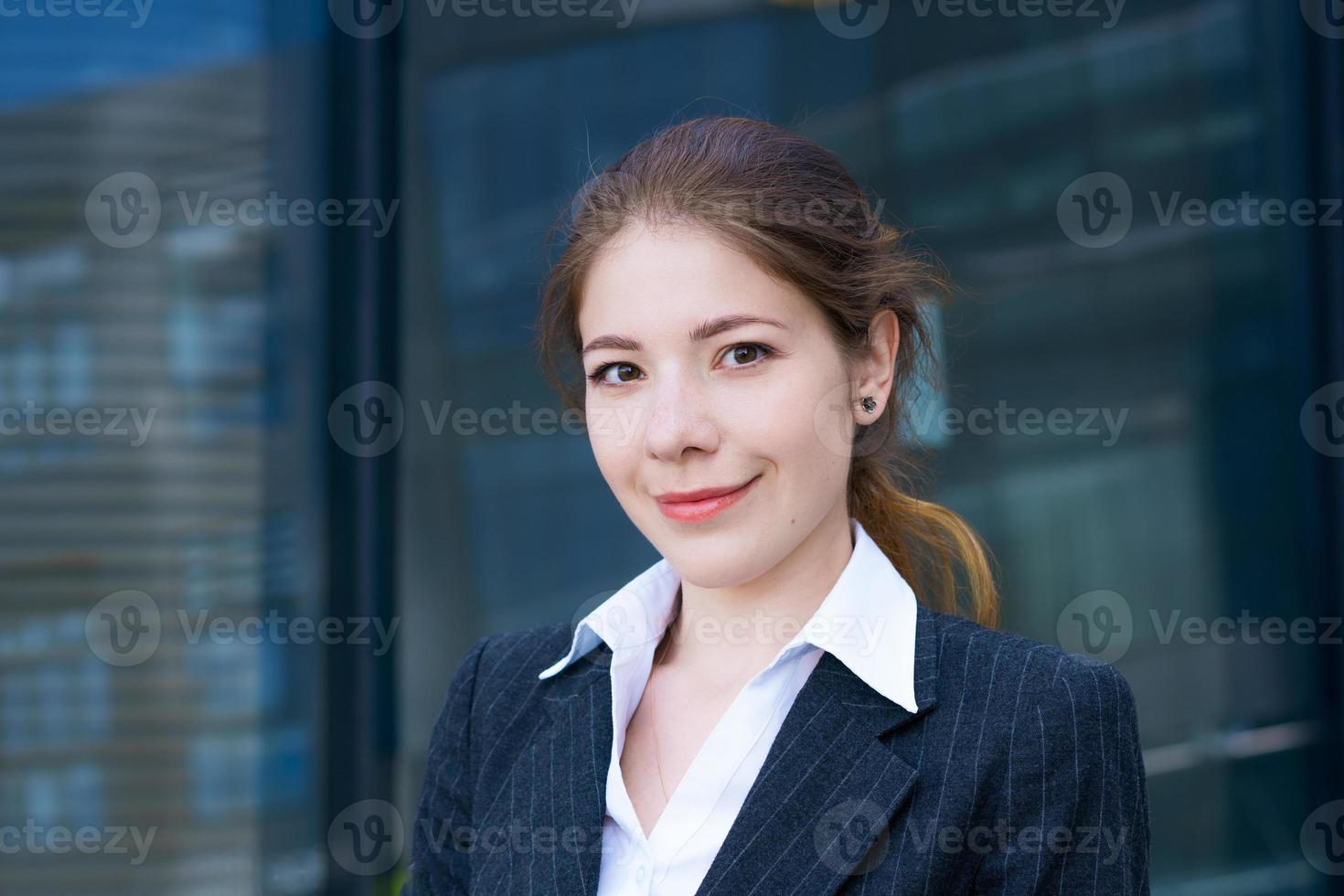 Business woman in suit uses smartphone. Big city with skyscrapers in background. Talking on the phone during the day photo