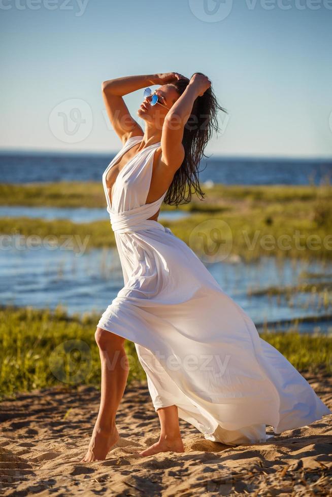 hermosa mujer en blanco vestir posando en el apuntalar foto