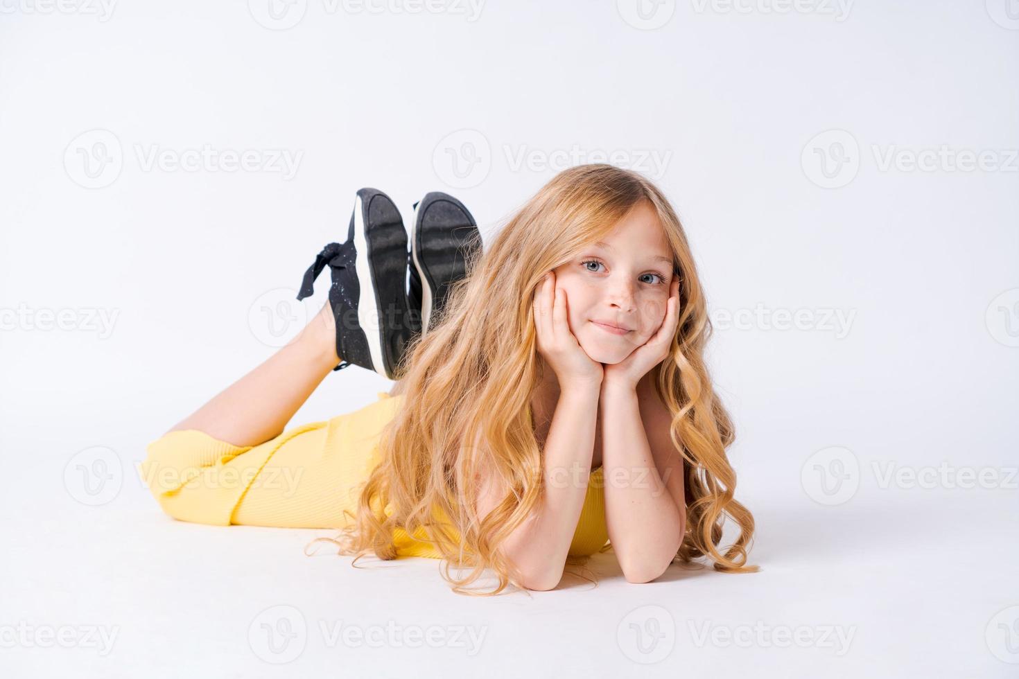 Studio portrait pretty girl with curly hair sitting on floor in studio smiling photo