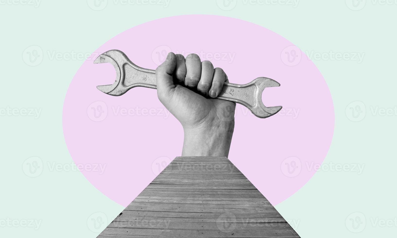 Art collage. Hand with a wrench with a wooden bridge. photo