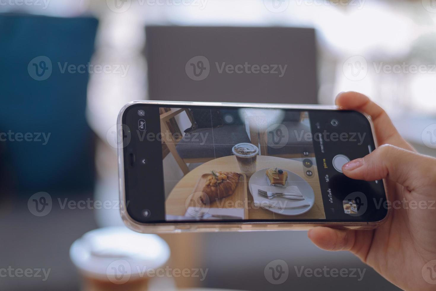 Woman taking a picture of food with a mobile phone in a cafe photo