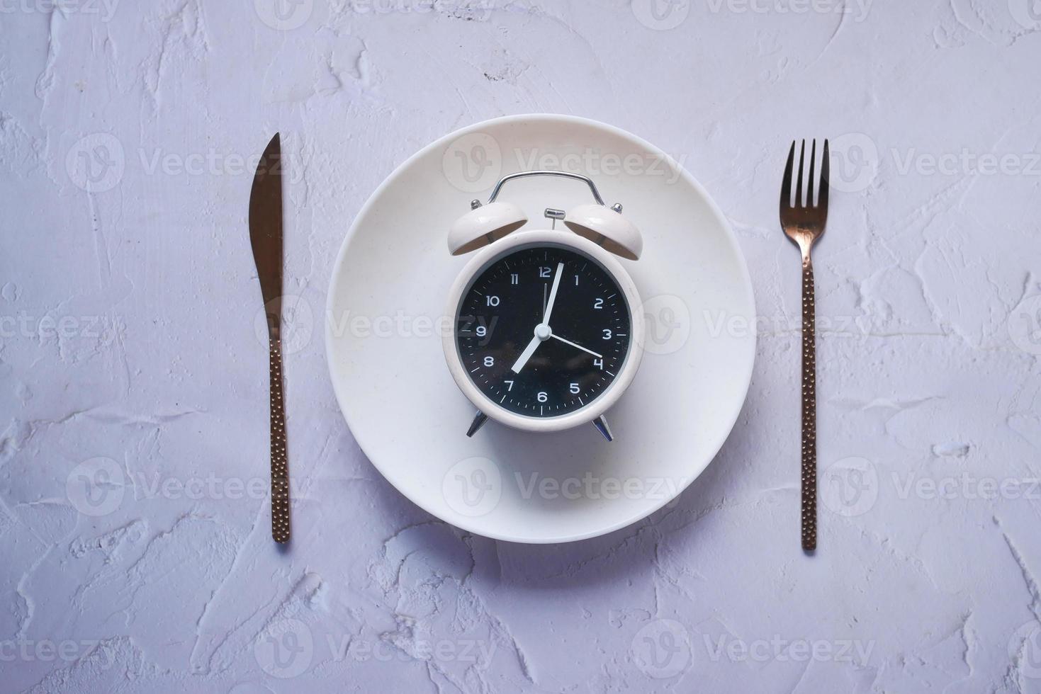 Alarm clock on plate on wooden table, top view. photo