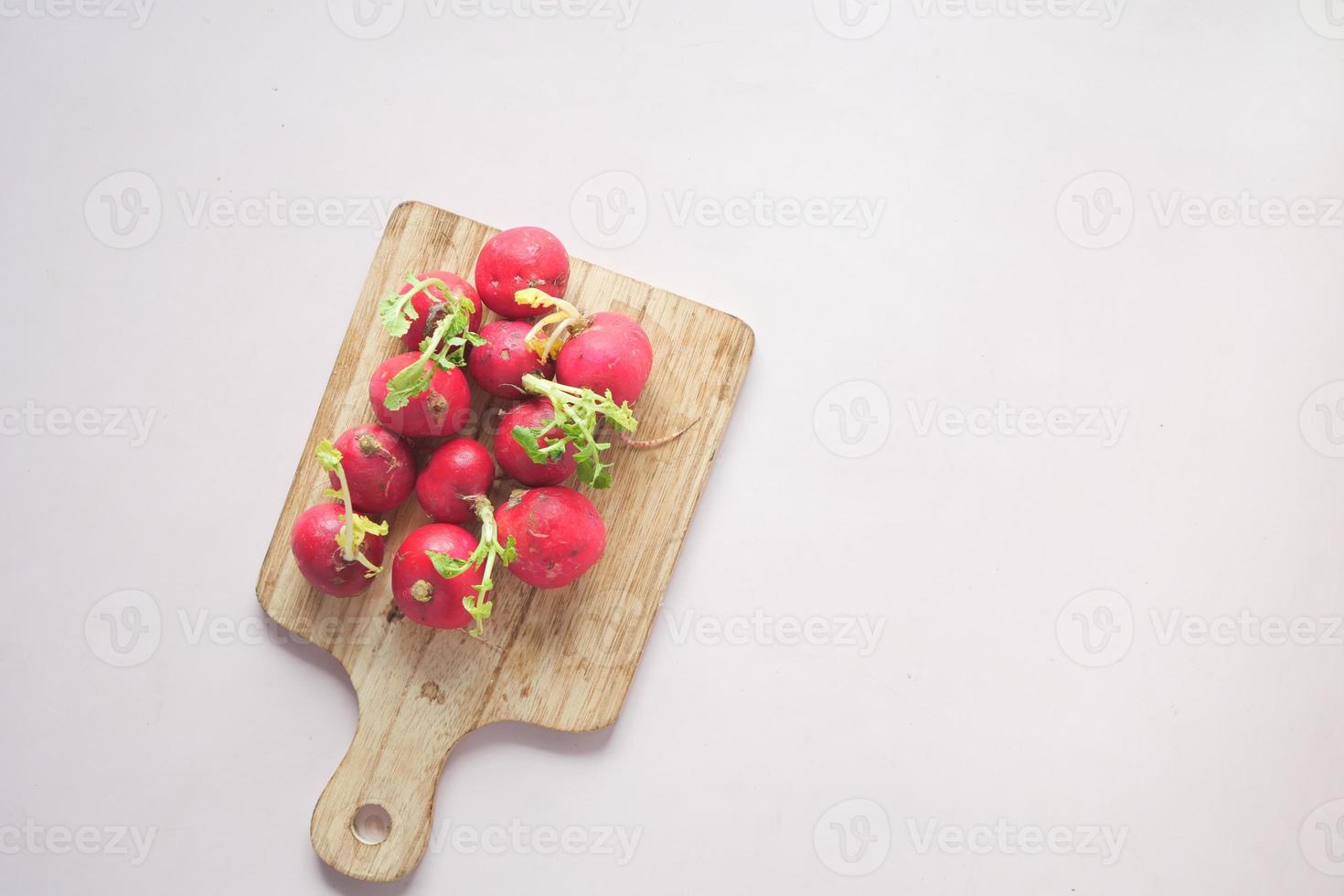 Fresh red radish bundle on chopping board on table photo