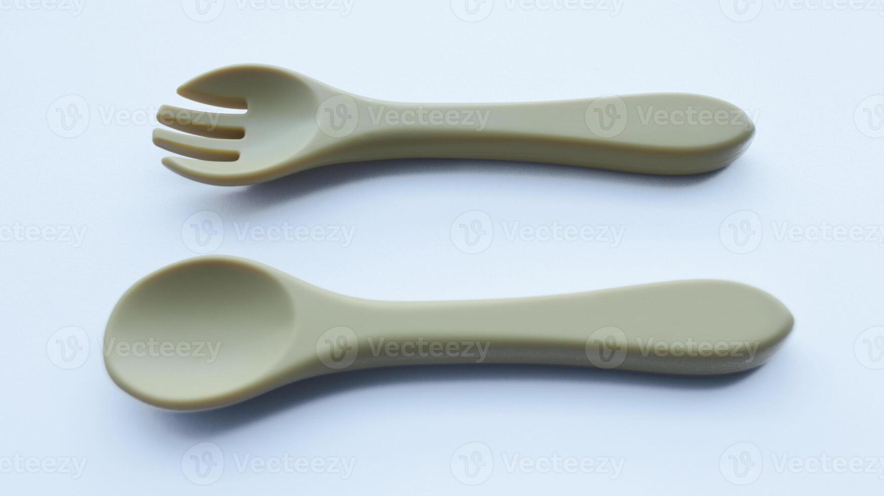 Brown silicone fork and spoon baby utensil isolated on white. photo