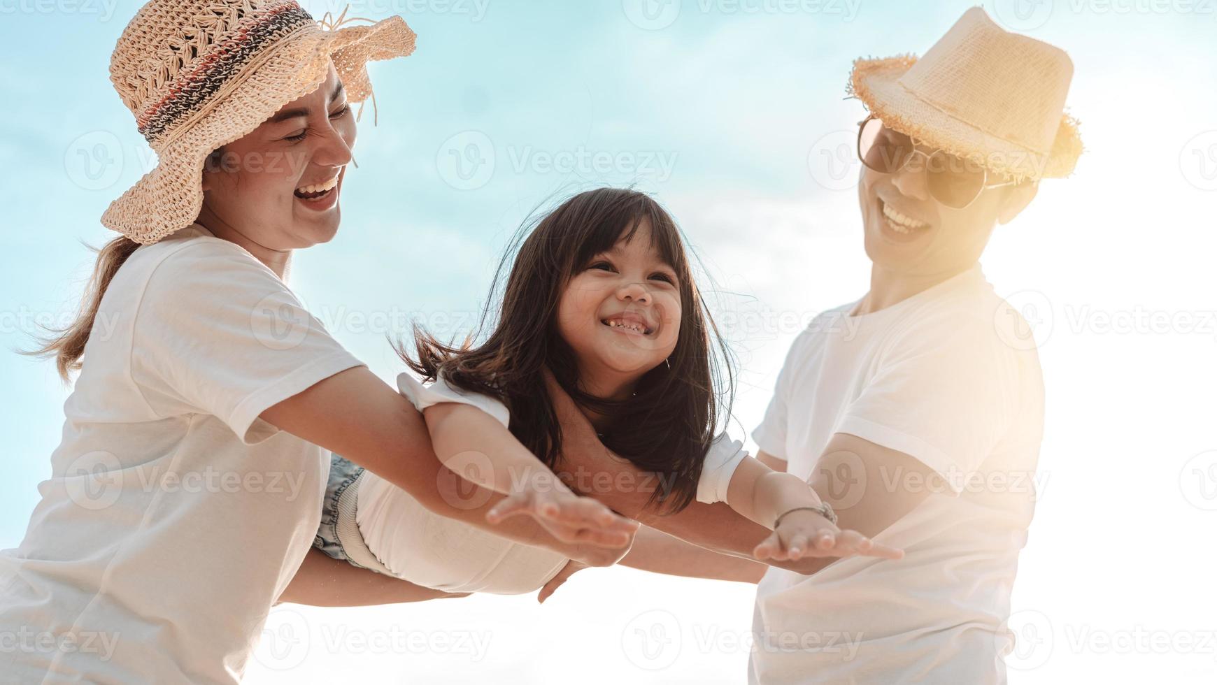 contento asiático familia disfrutar el mar playa a consistente padre, madre y hija teniendo divertido jugando playa en verano vacaciones en el Oceano playa. contento familia con vacaciones hora estilo de vida concepto. foto