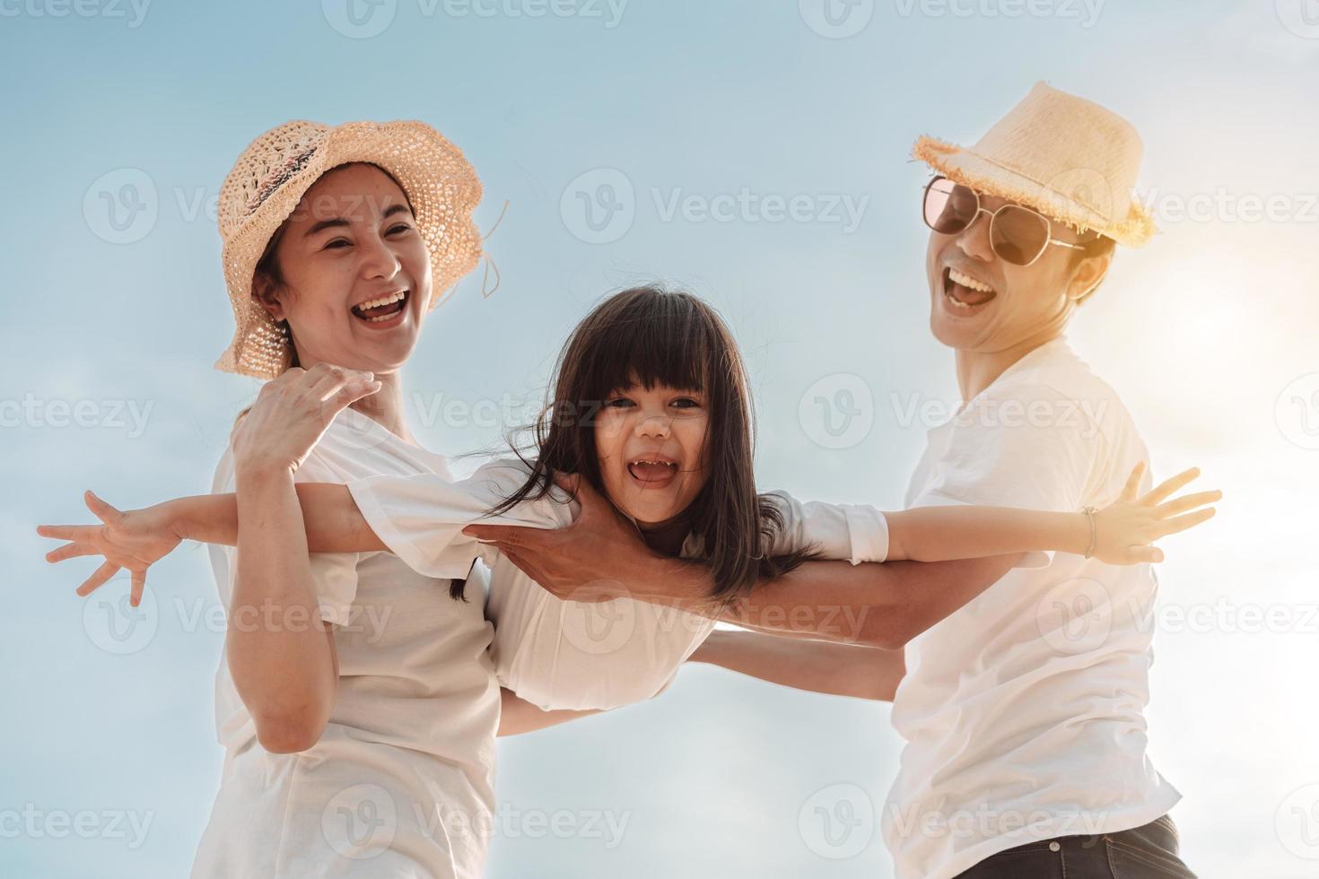 Happy asian family enjoy the sea beach at consisting father, mother and daughter having fun playing beach in summer vacation on the ocean beach. Happy family with vacations time lifestyle concept. photo