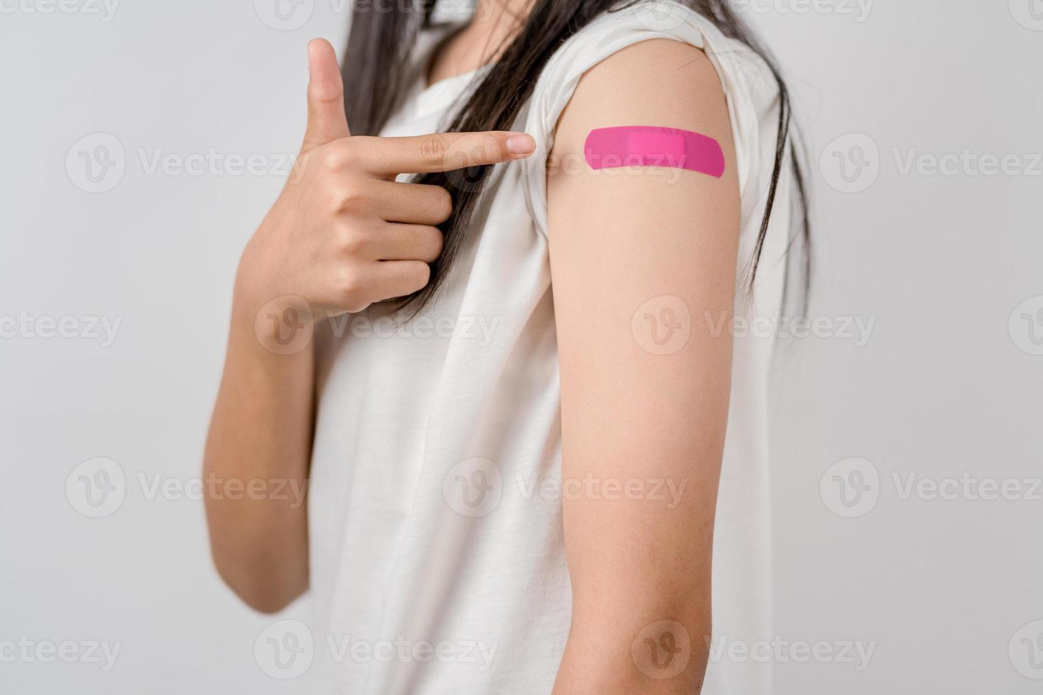 Young woman after getting a vaccine. showing shoulder arm with bandage after receiving vaccination, herd immunity, side effect, booster dose, vaccine passport and Coronavirus pandemic photo