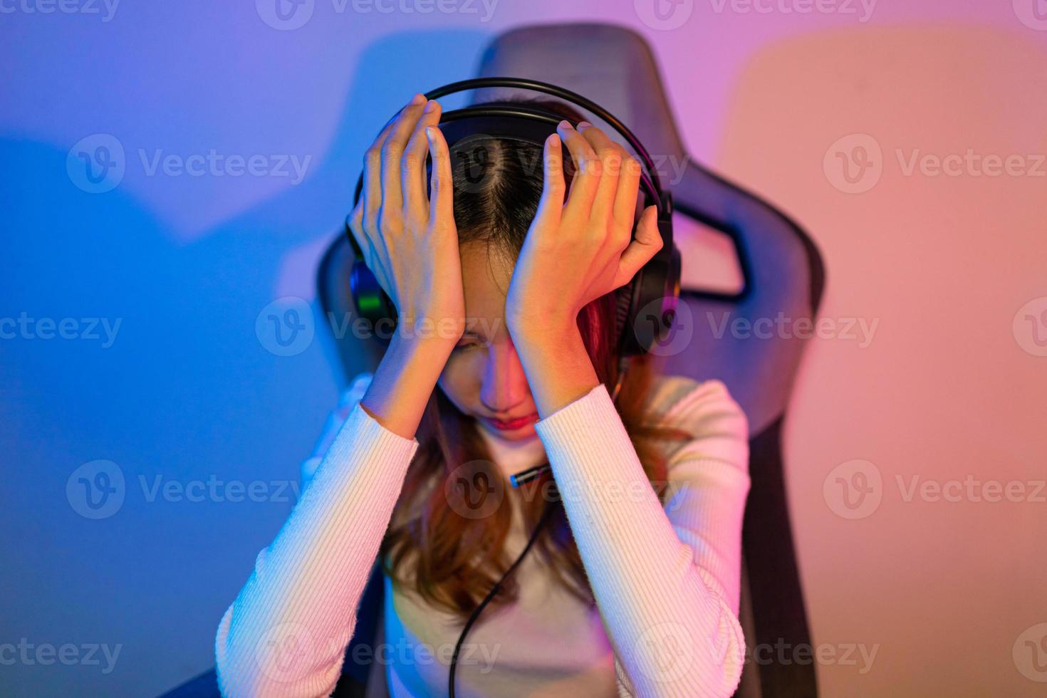 Game over loss match. Asian game with headphones playing online video game on computer PC neon light at home feeling sad disappointed about game losing, tournament player E-Sport photo