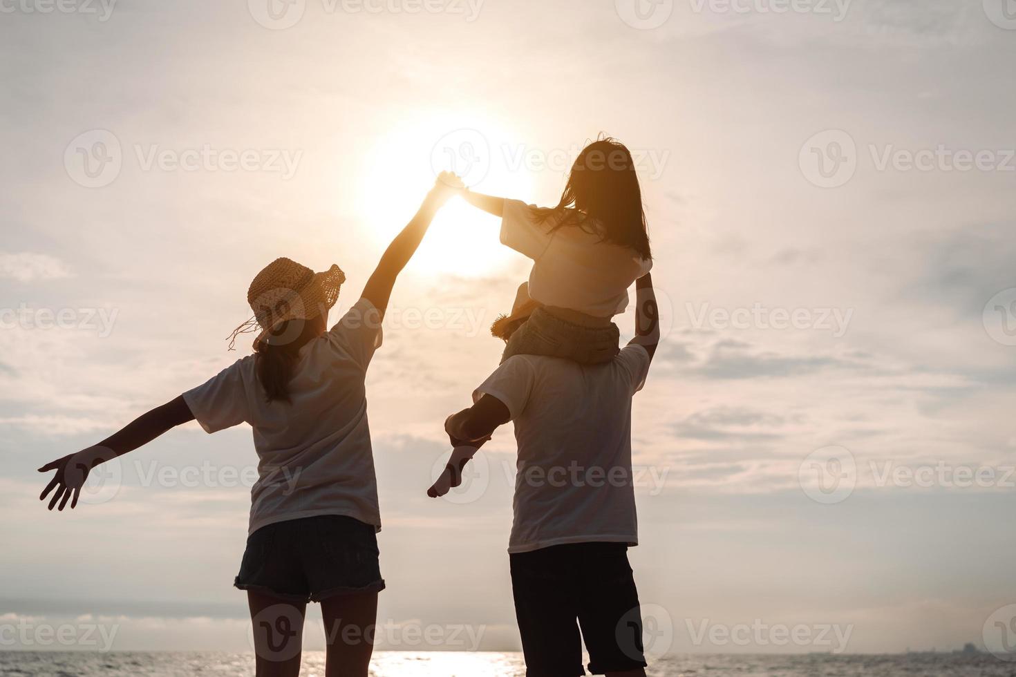 contento asiático familia disfrutar el mar playa a consistente padre, madre y hija teniendo divertido jugando playa en verano vacaciones en el Oceano playa. contento familia con vacaciones hora estilo de vida concepto. foto
