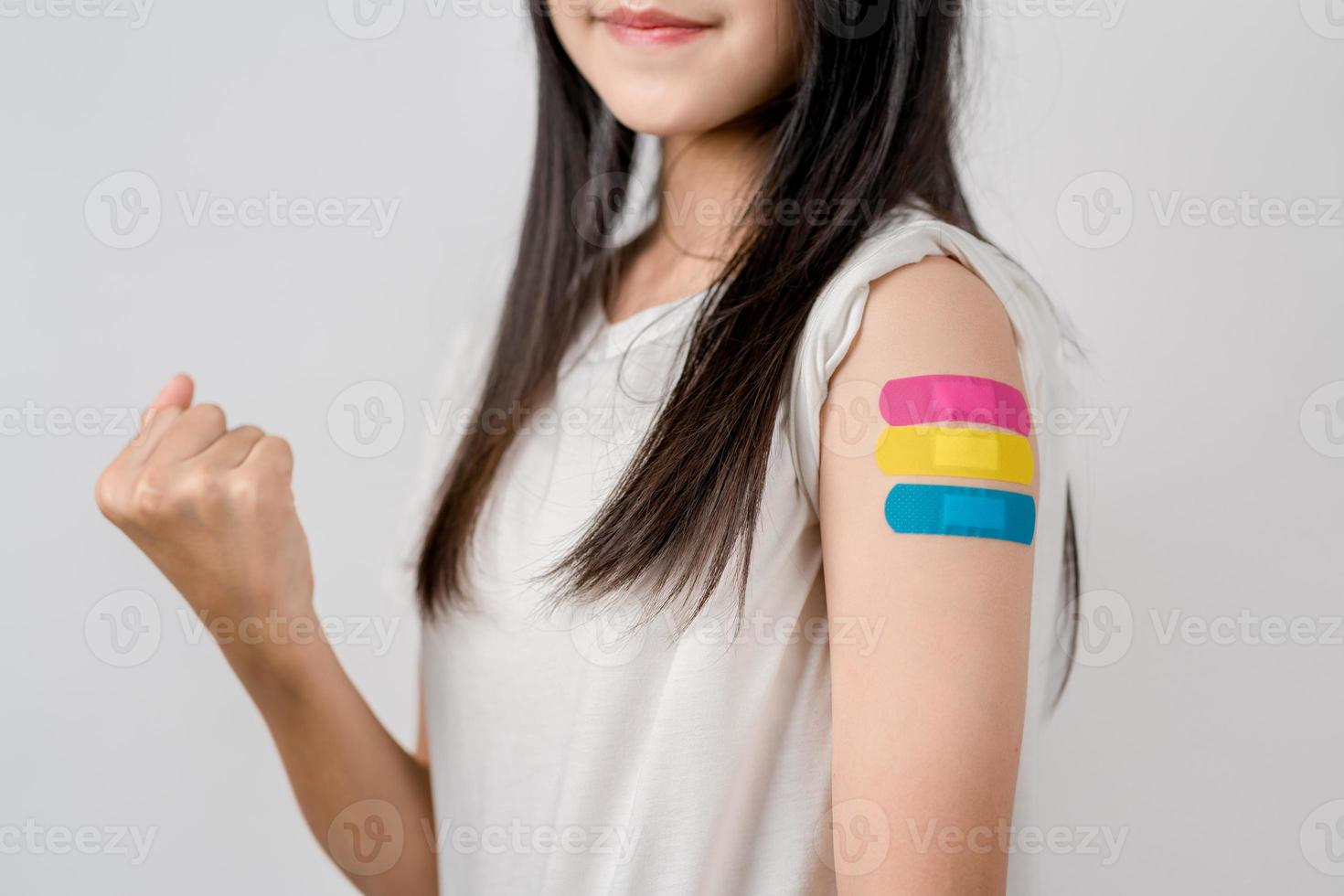 Happy young woman show victory sign after getting a vaccine. showing shoulder with bandage after receiving vaccination, herd immunity, side effect, booster dose, vaccine passport and Coronavirus photo