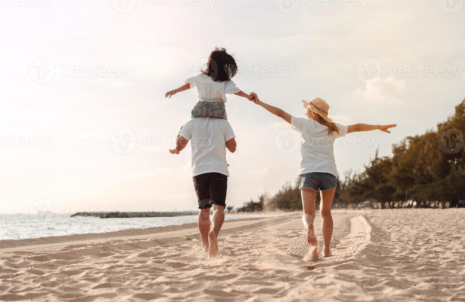 contento asiático familia disfrutar el mar playa a consistente padre, madre y hija teniendo divertido jugando playa en verano vacaciones en el Oceano playa. contento familia con vacaciones hora estilo de vida concepto. foto