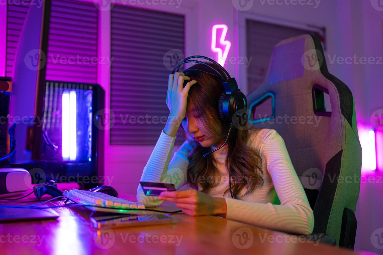 Top up online game with credit card concept. Gamer and E-Sport online of Asian woman playing online computer video game with lighting effect, broadcast streaming live at home. Gamer and E-Sport gaming photo