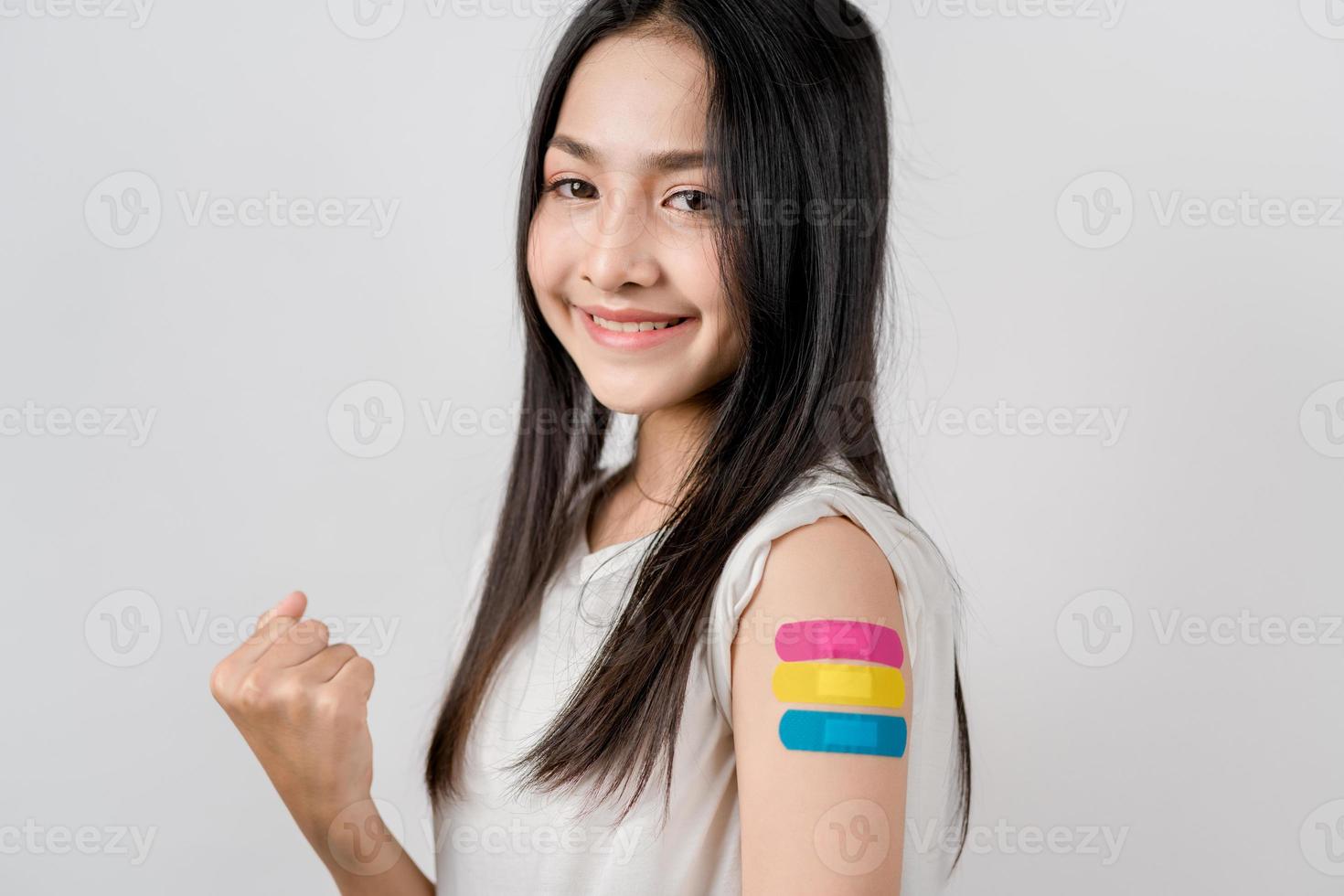 Happy young woman show victory sign after getting a vaccine. showing shoulder with bandage after receiving vaccination, herd immunity, side effect, booster dose, vaccine passport and Coronavirus photo