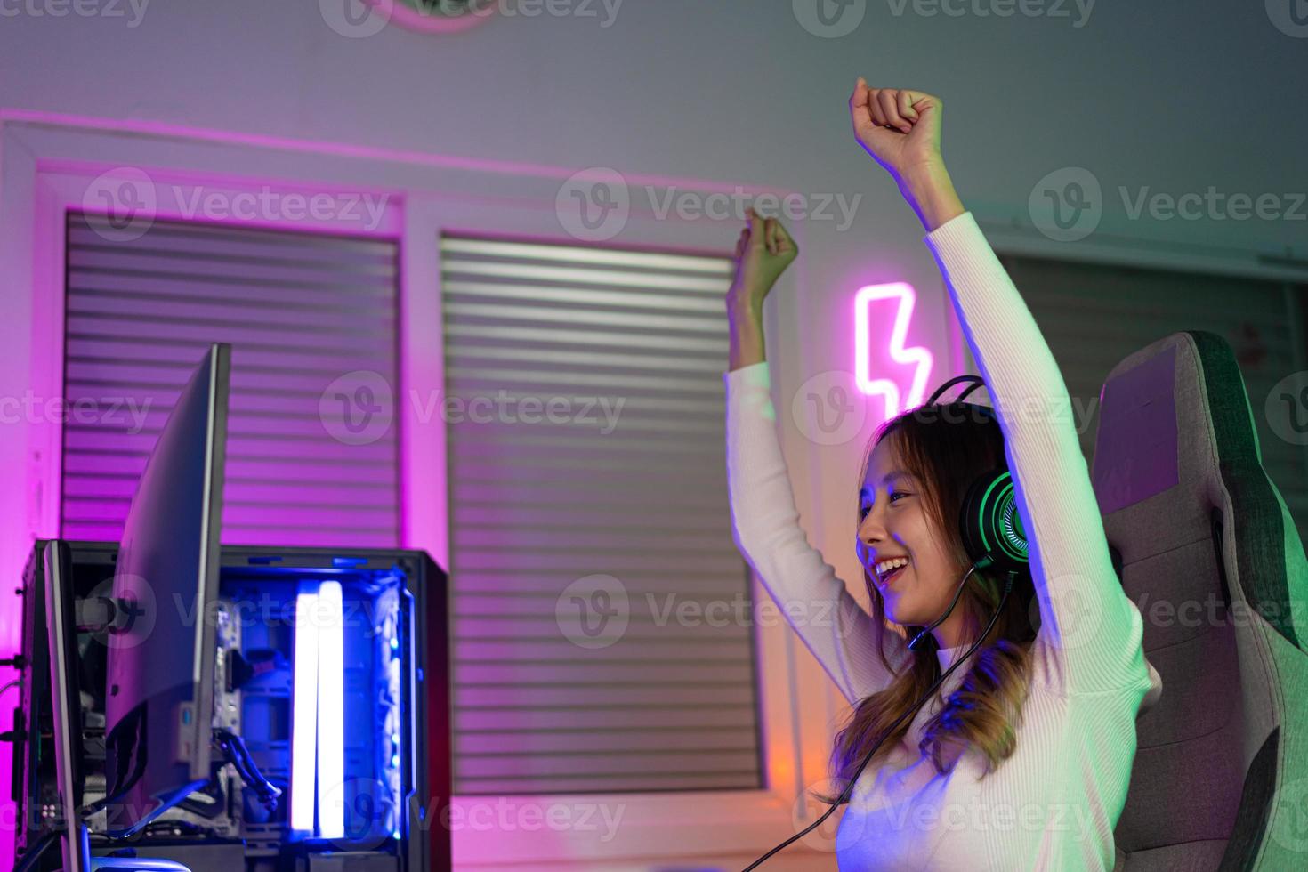 Asian gamer playing online video game winning excited on PC with lighting effect, broadcast streaming live at home. Gamer and E-Sport online gaming technology Championship tournament gamer concept. photo