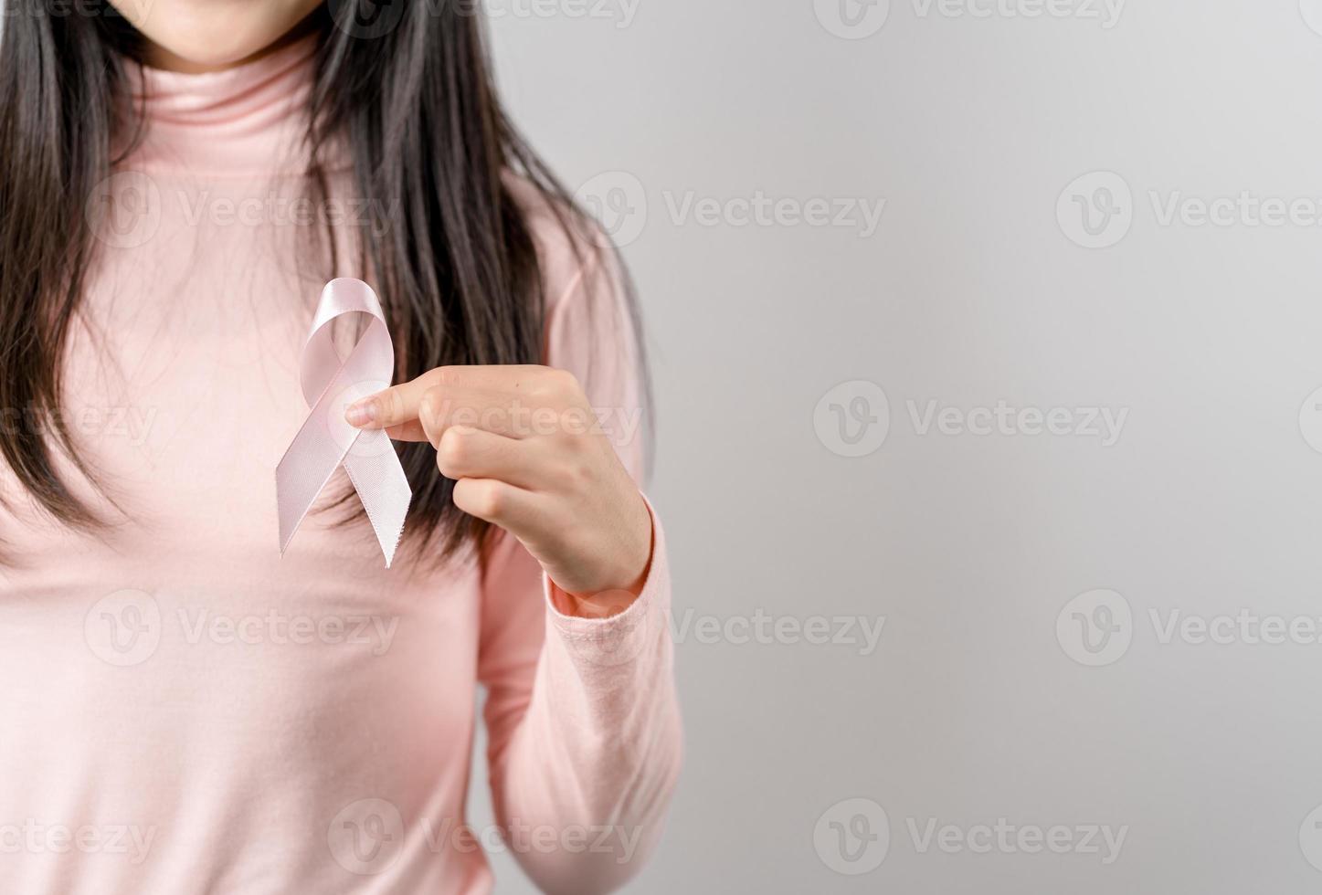 woman hands holding pink ribbon, Breast cancer awareness, world cancer day, national cancer survivor day in february concept. photo