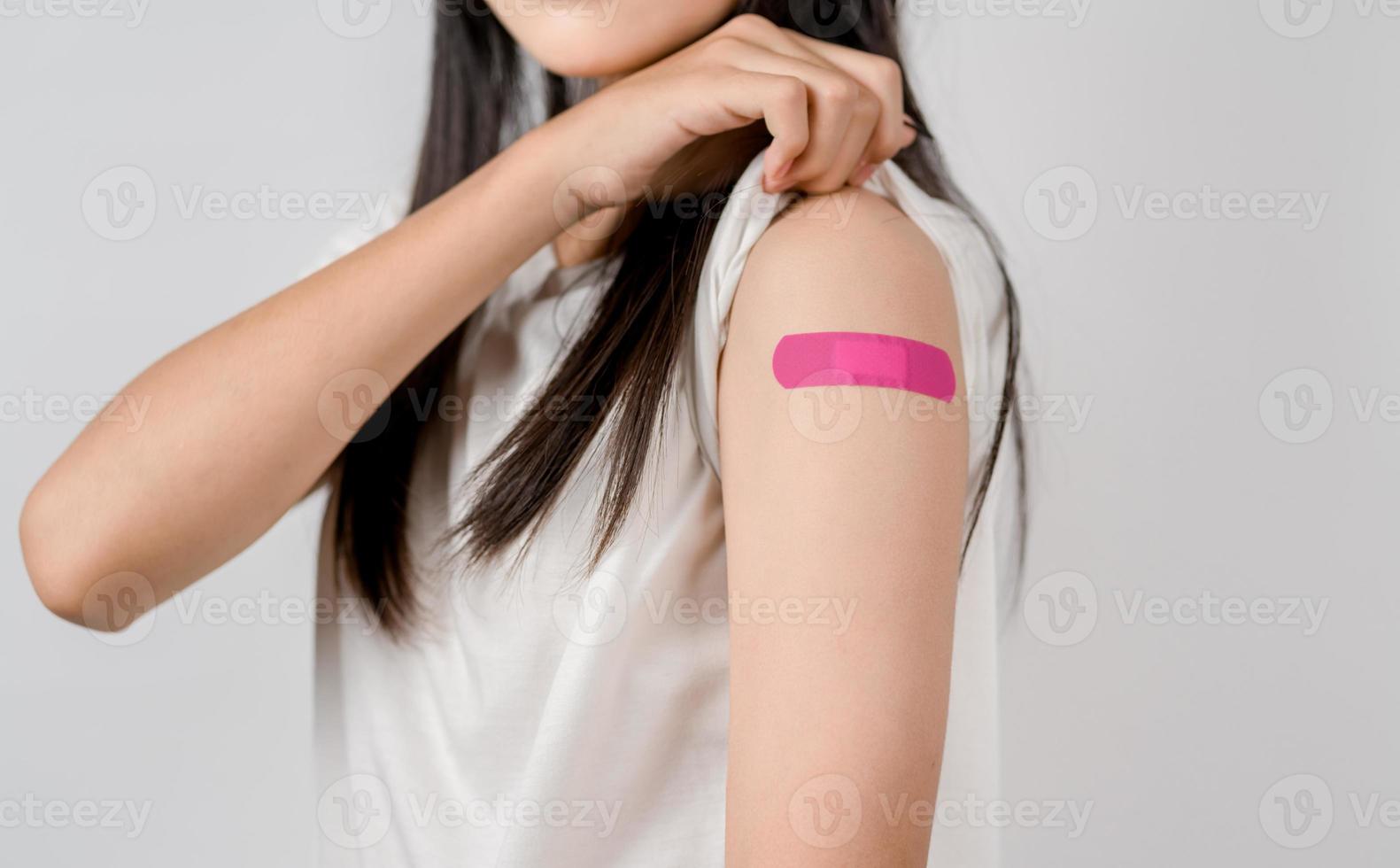 Happy young woman after getting a vaccine. showing shoulder arm with bandage after receiving vaccination, herd immunity, side effect, booster dose, vaccine passport and Coronavirus pandemic photo