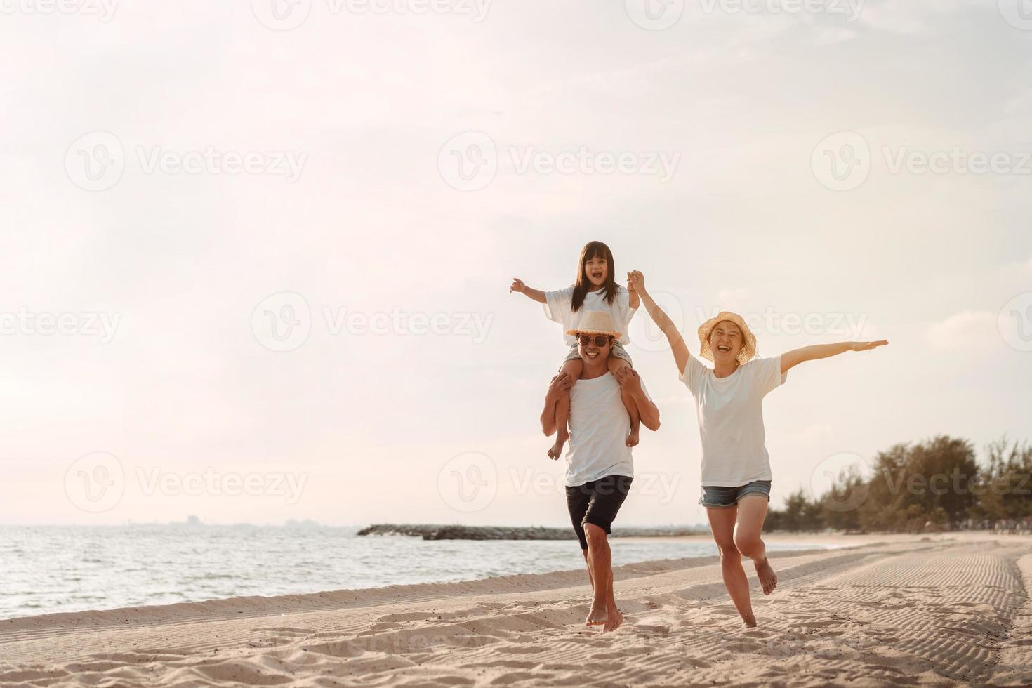 Happy asian family enjoy the sea beach at consisting father, mother and daughter having fun playing beach in summer vacation on the ocean beach. Happy family with vacations time lifestyle concept. photo