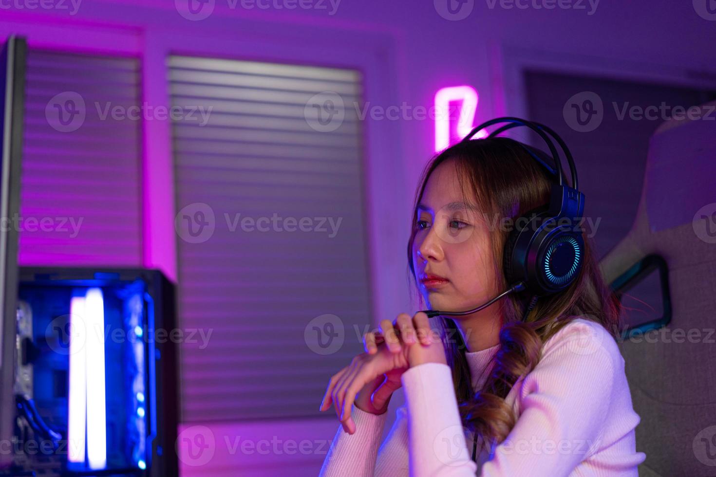 Wrist pain concept. Gamer and E-Sport online of Asian woman playing online computer video game with lighting effect, broadcast streaming live at home. her use her wrist for a long time. photo