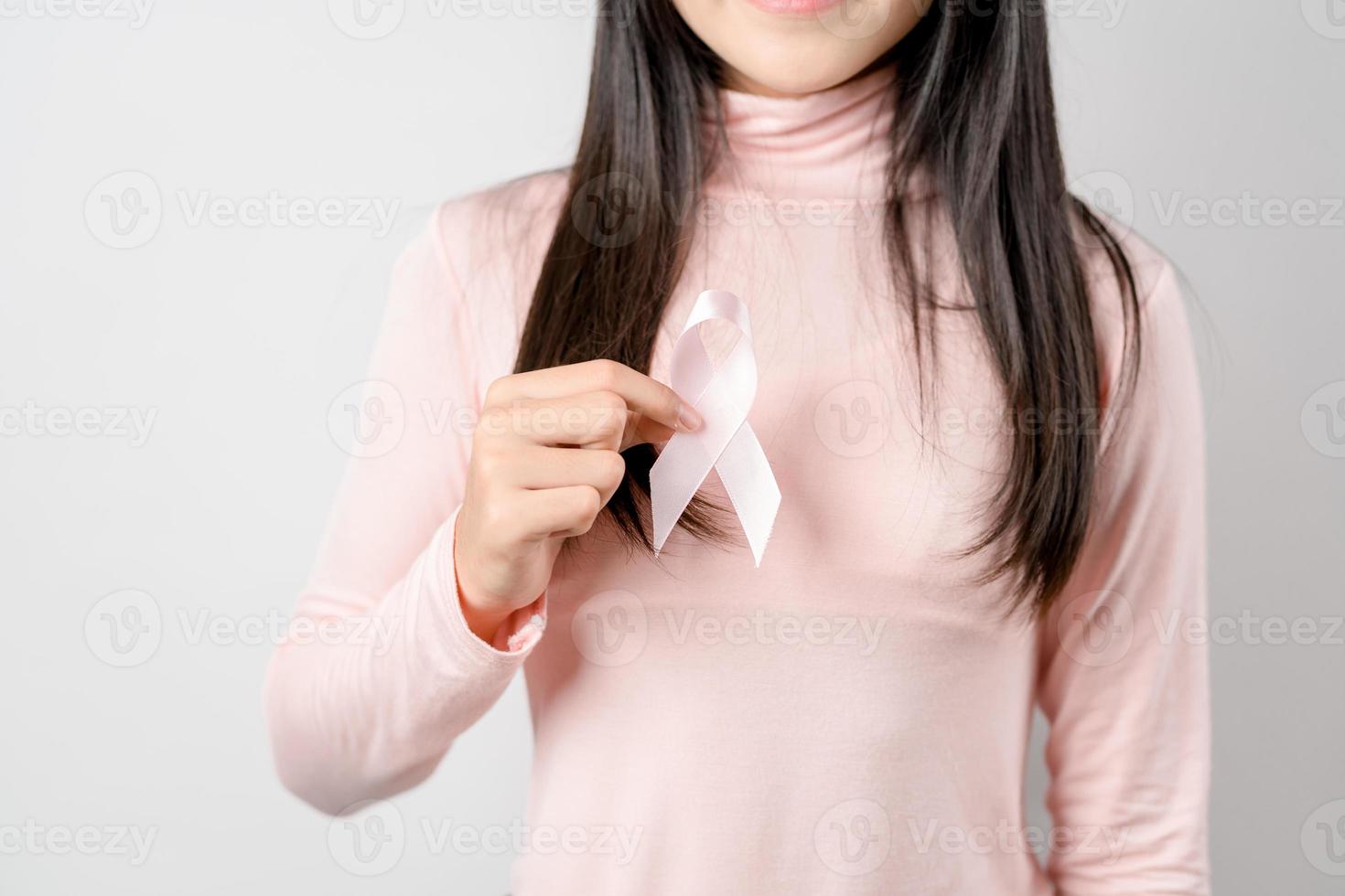 woman hands holding pink ribbon, Breast cancer awareness, world cancer day, national cancer survivor day in february concept. photo