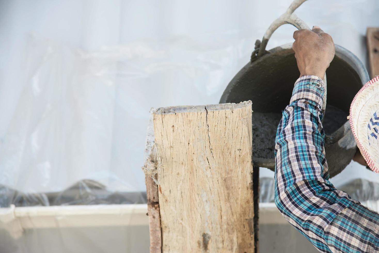 constructor contratista hombre trabajo mezcla hormigón en industria trabajo proyecto, torrencial mojado líquido material dentro el columna formar en construcción sitio como profesional empleo foto