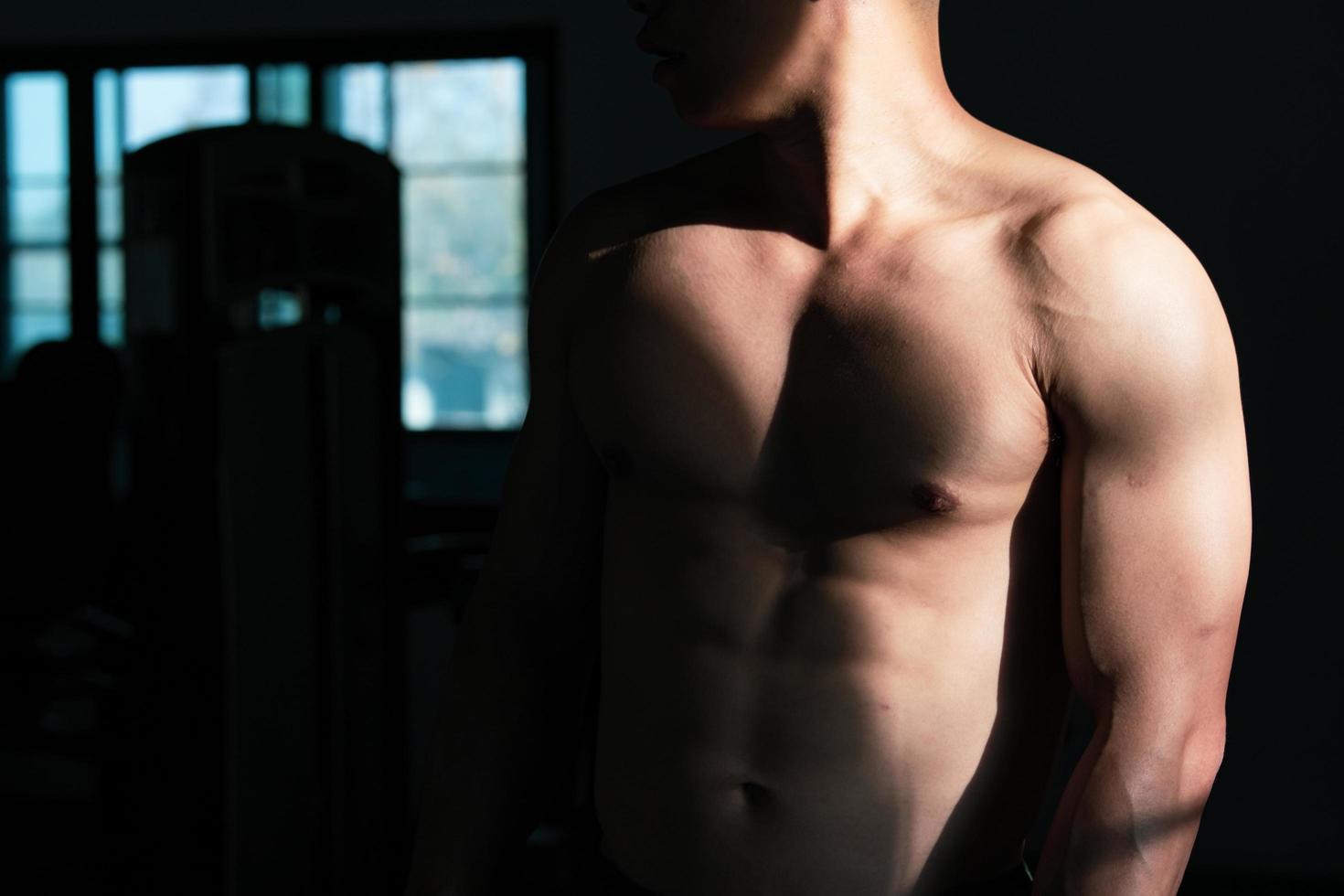Sexy body of muscular young soldier Asian man in gym. Concept of health care, exercise fitness, Strong muscle mass, body enhancement, fat reduction for men's health supplement product presentation. photo