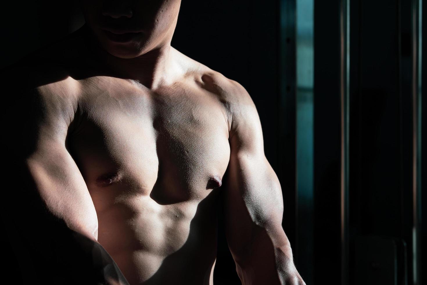 Sexy body of muscular young soldier Asian man in gym. Concept of health care, exercise fitness, Strong muscle mass, body enhancement, fat reduction for men's health supplement product presentation. photo