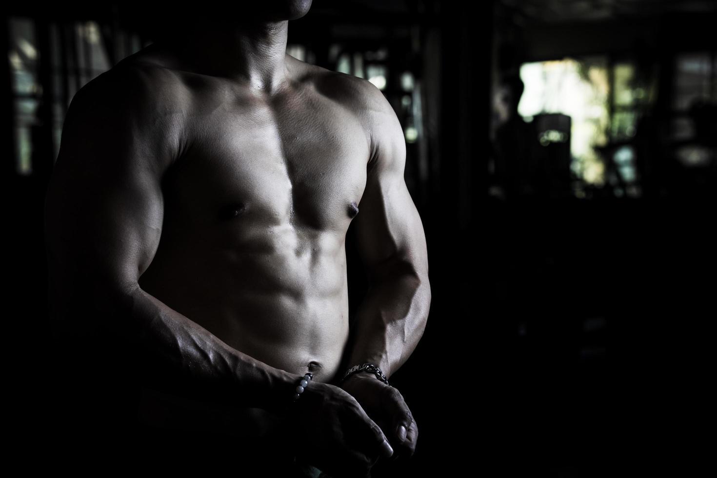 Sexy body of muscular young Asian man in gym. Concept of health care, exercise fitness, Strong muscle mass, body enhancement, fat reduction for men's health supplement product presentation. photo