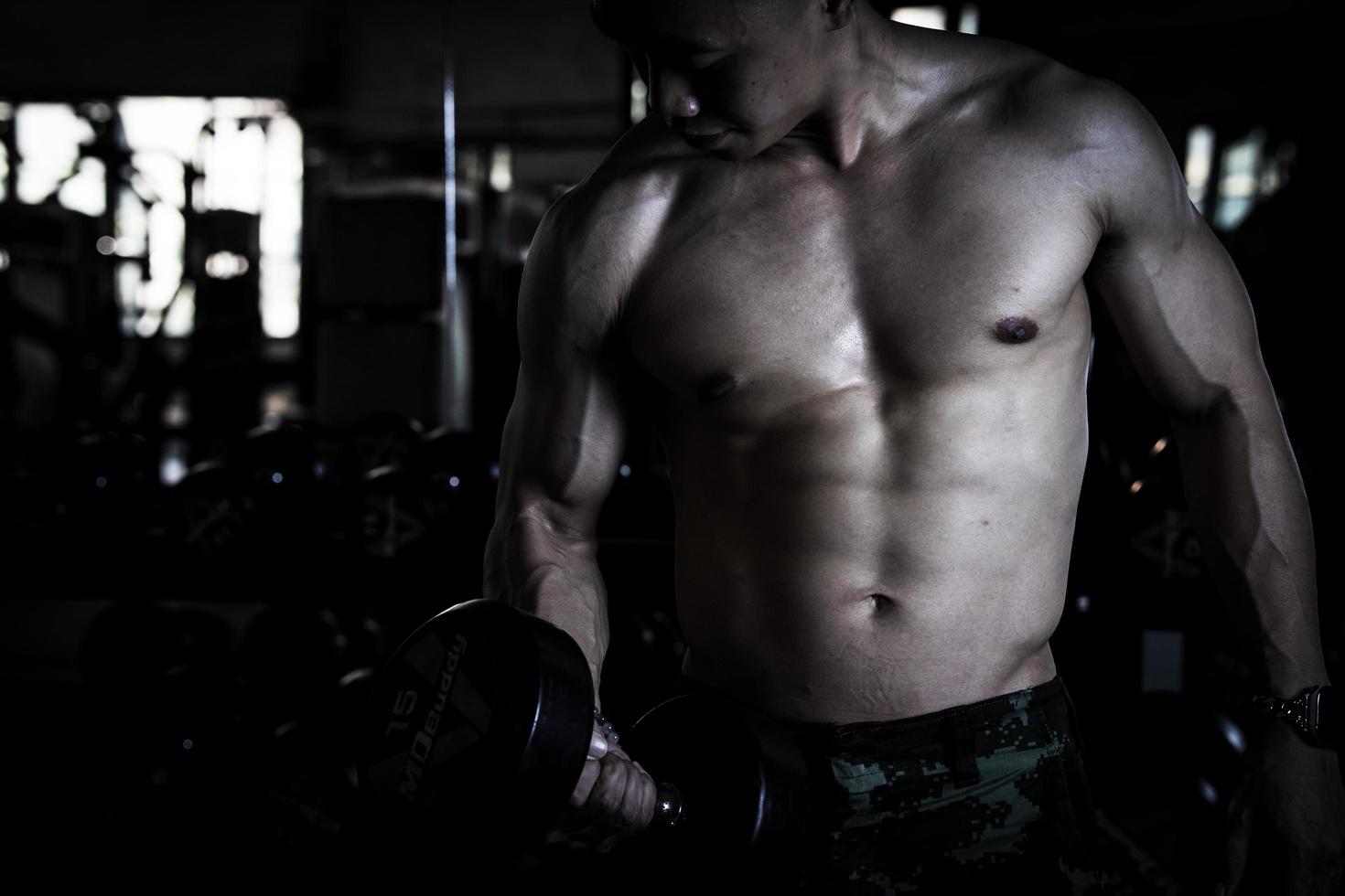 Sexy body of muscular young soldier Asian man in gym. Concept of health care, exercise fitness, Strong muscle mass, body enhancement, fat reduction for men's health supplement product presentation. photo