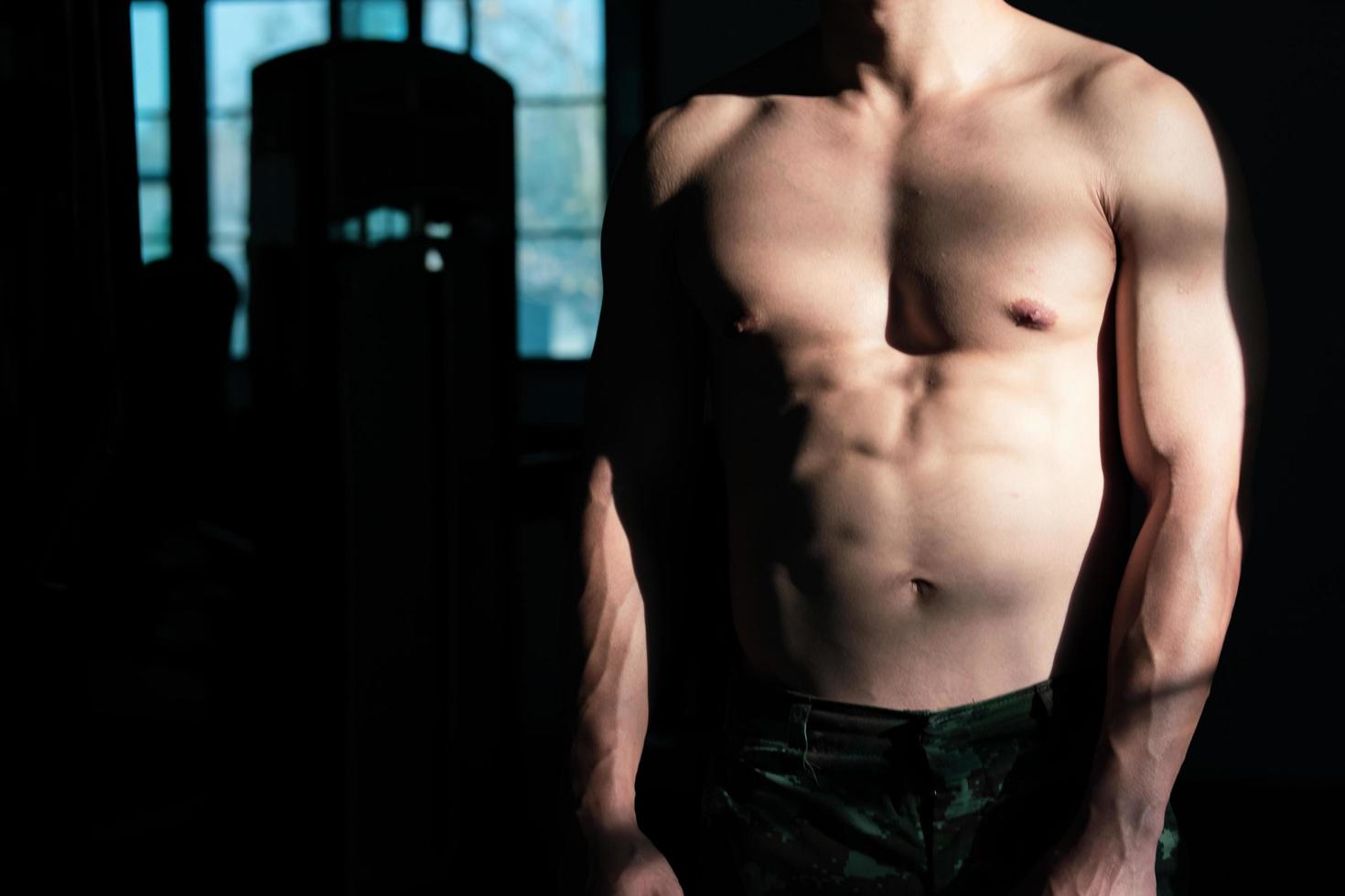 Sexy body of muscular young soldier Asian man in gym. Concept of health care, exercise fitness, Strong muscle mass, body enhancement, fat reduction for men's health supplement product presentation. photo