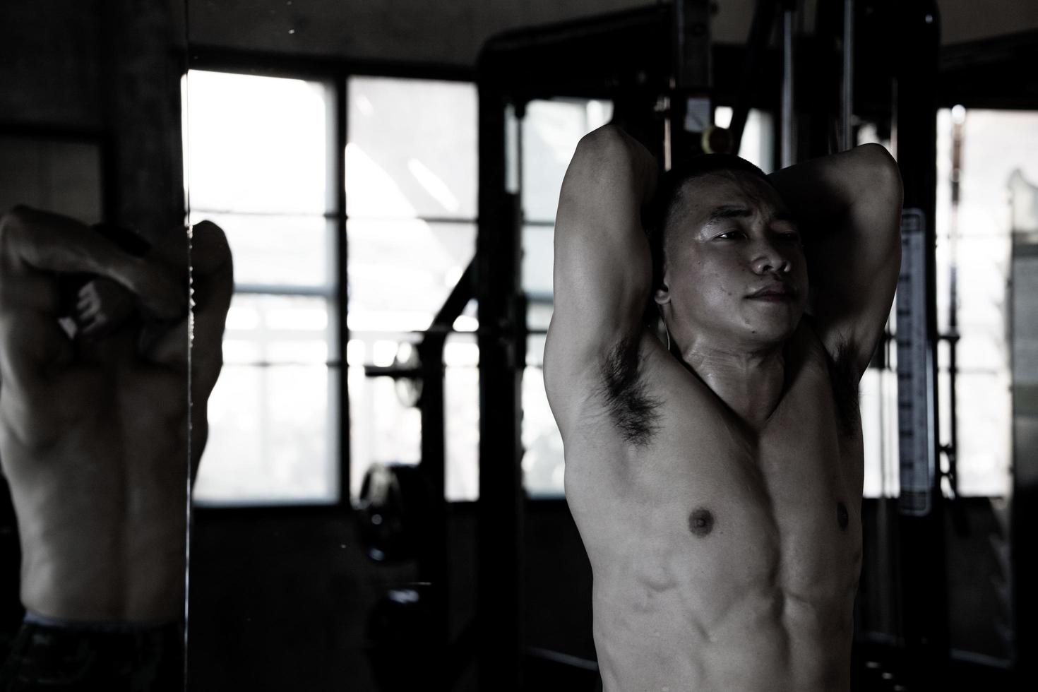 Sexy body of muscular young soldier Asian man in gym. Concept of health care, exercise fitness, Strong muscle mass, body enhancement, fat reduction for men's health supplement product presentation. photo