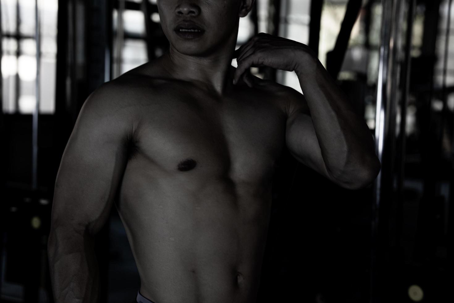 Sexy body of muscular young soldier Asian man in gym. Concept of health care, exercise fitness, Strong muscle mass, body enhancement, fat reduction for men's health supplement product presentation. photo