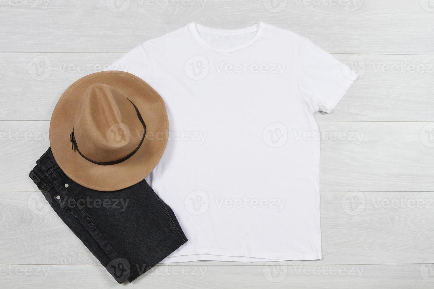 White T-Shirt mockup. Template blank shirt top view on white wooden background. Spring summer outfit on wood floor. Woman fashion clothes. Autumn look of today. Female Jeans, hat accessories photo